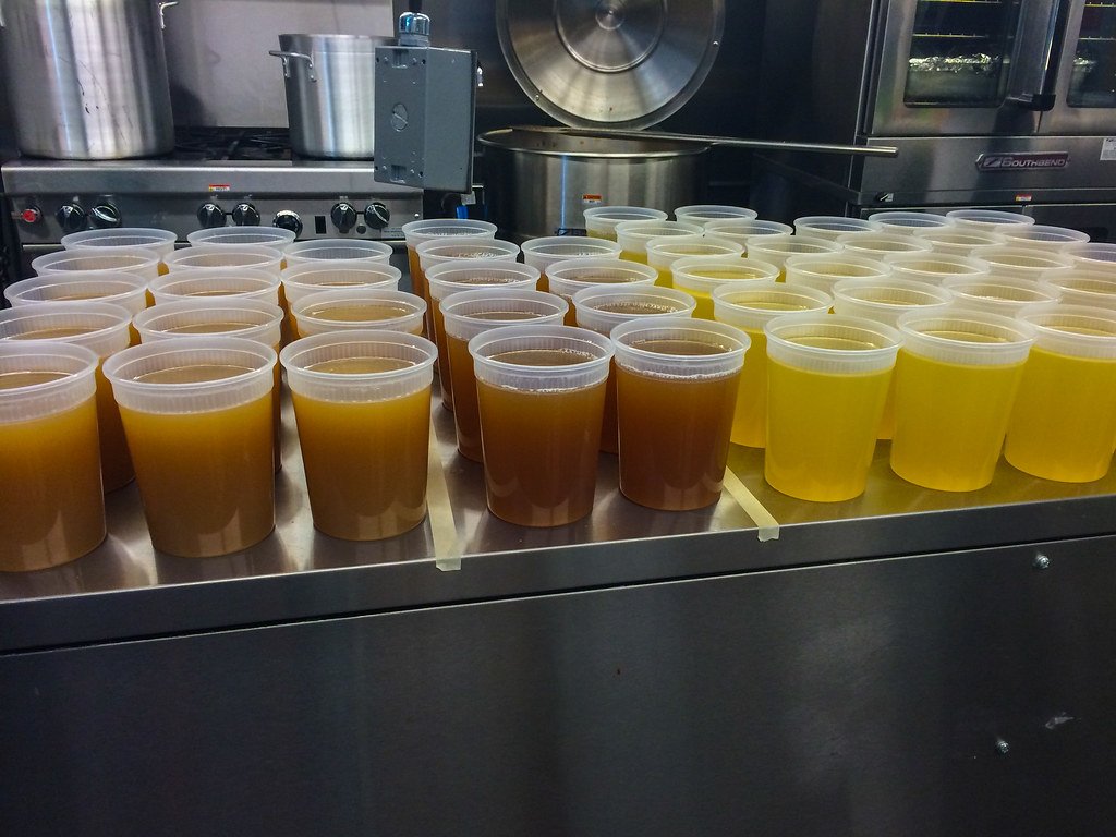 Rows of rich bone broth cooling in clear deli containers.