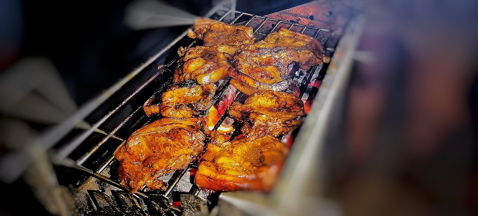 Bone-in pork chops browning over a narrow charcoal grill.