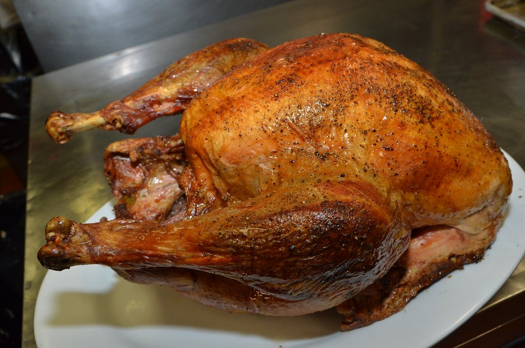 A whole roasted turkey with evenly browned skin on a plain platter.